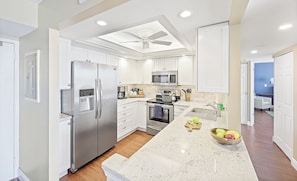 A modern kitchen with stainless steel appliances, white cabinetry, and a central island.