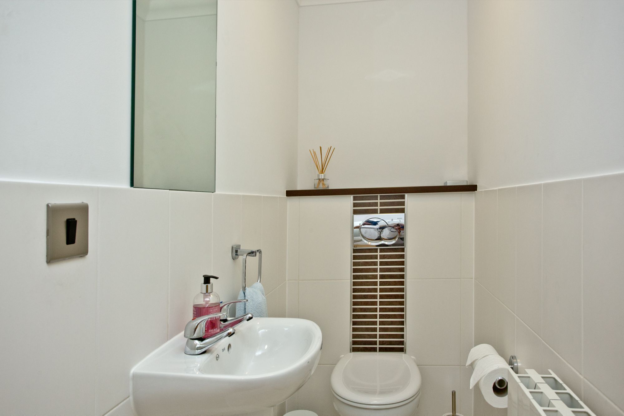 Een badkamer met een wit wastafel, toilet en spiegel.