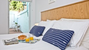 A neatly made bed with two pillows, a tray with croissants, juice glasses, and a newspaper.