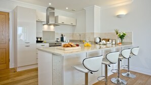 A modern kitchen with a central island, bar stools, and a wooden door.