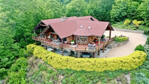 Eine Holzhütte mit rotem Dach, einer Terrasse und einem Steinweg, der zum Eingang führt.
