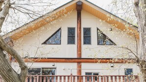 A two-story house with a wooden fence, a central chimney, and a triangular roof. - Izu House Luxury Log with Cozy Fireplace (Ito)