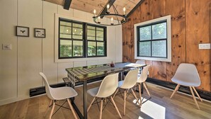A dining area with a wooden table, four chairs, and a chandelier. - Sleek Cabin w/ Deck, 8 Miles to Mount Snow & Hikes (Wilmington)