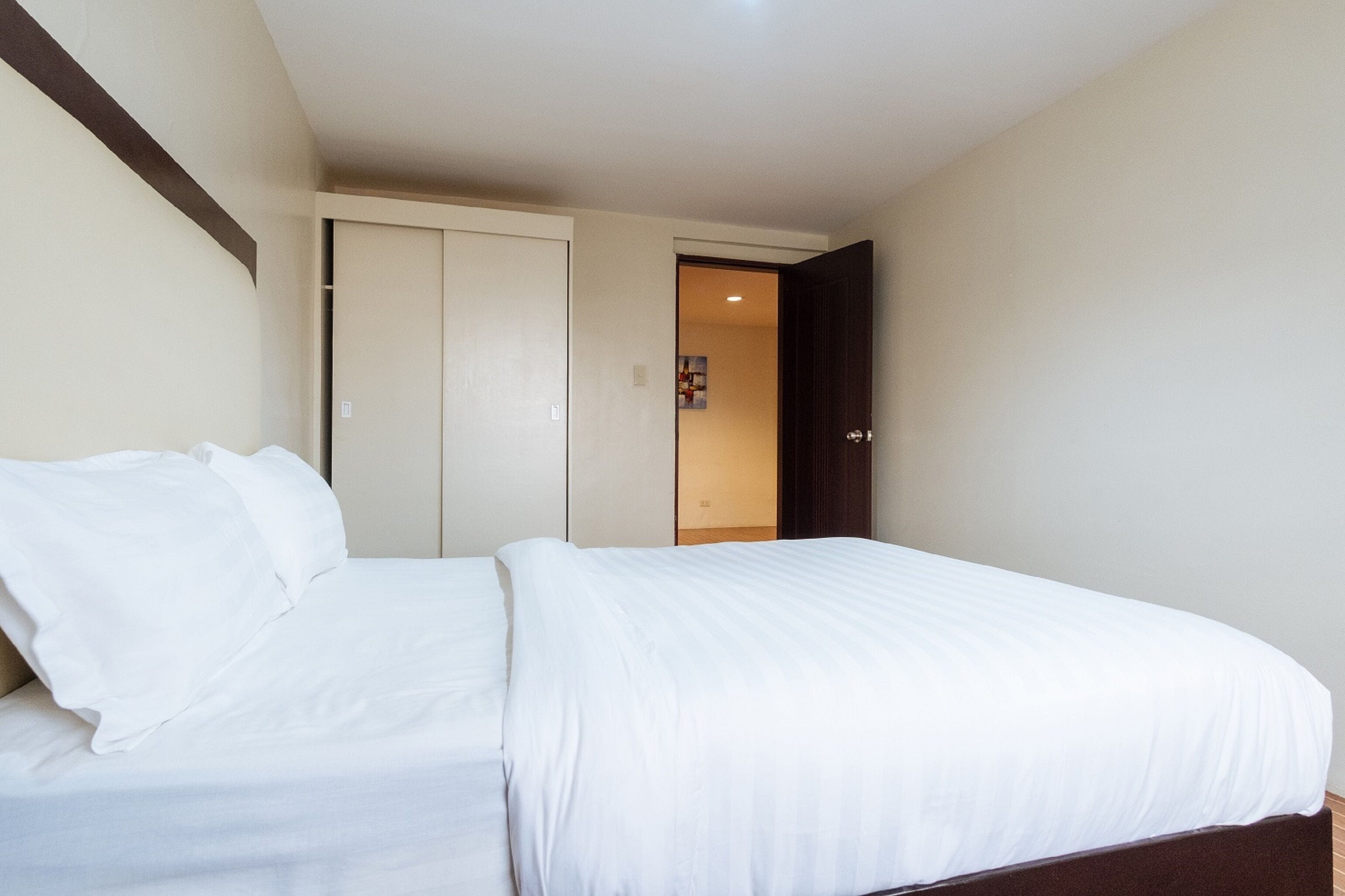Ein Hotelzimmer mit einem Bett, einem Kleiderschrank und einer Tür zu einem weiteren Raum.