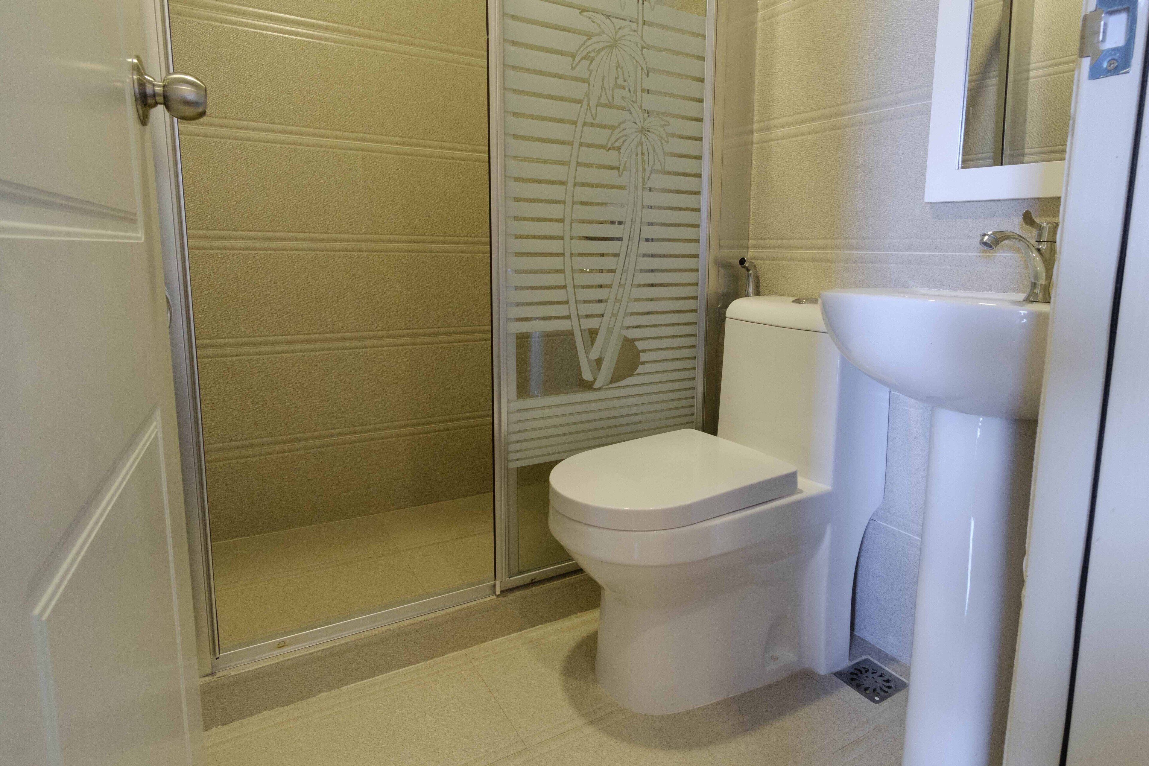 Une salle de bain comprenant des toilettes, un lavabo et une douche séparée par une paroi en verre.