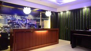 A reception area with a wooden desk, a cityscape mural, and a piano. - Northpointe Residences (Quezon City)