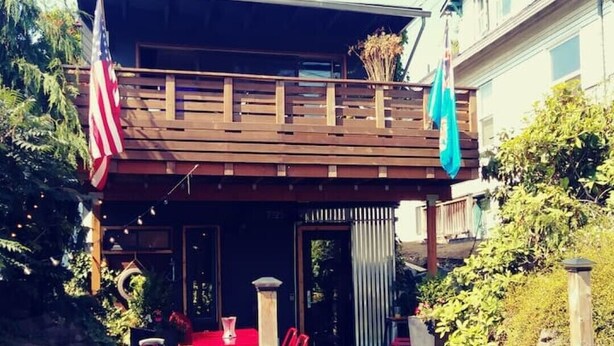 Une terrasse en bois avec une boîte aux lettres portant le numéro 7325, un barbecue et un drapeau.