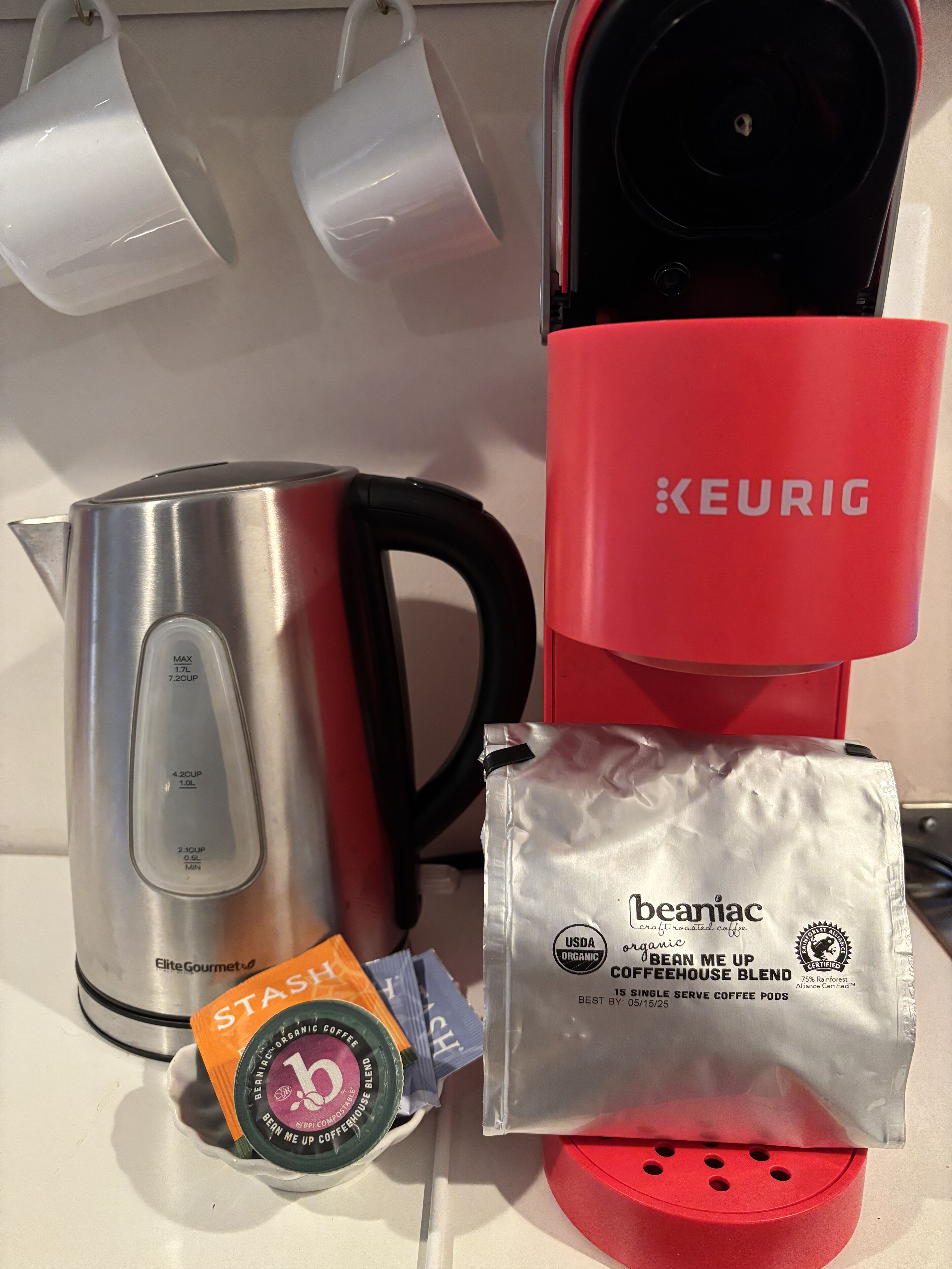 Une machine à café Keurig, une bouilloire en acier inoxydable et un paquet de capsules de café biologique.