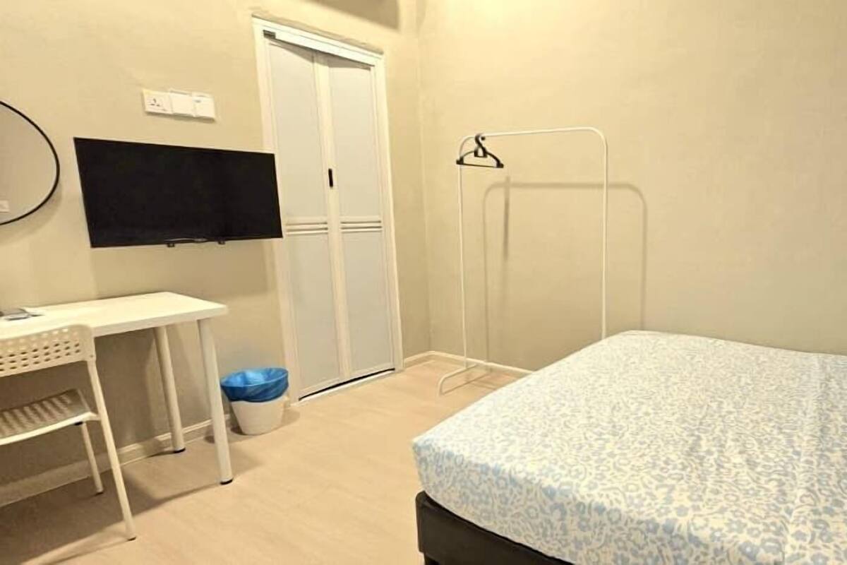A bedroom with a bed, a desk, a chair, a TV, and a wardrobe.