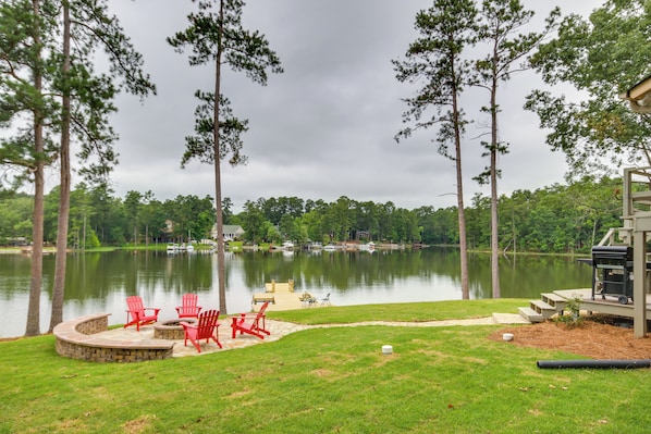Relax by the serene lake with a fire pit and Adirondack chairs.