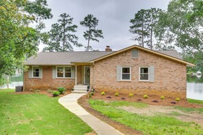 Stunning two-story home with a central entrance, flanked by windows, set amidst a serene natural setting.