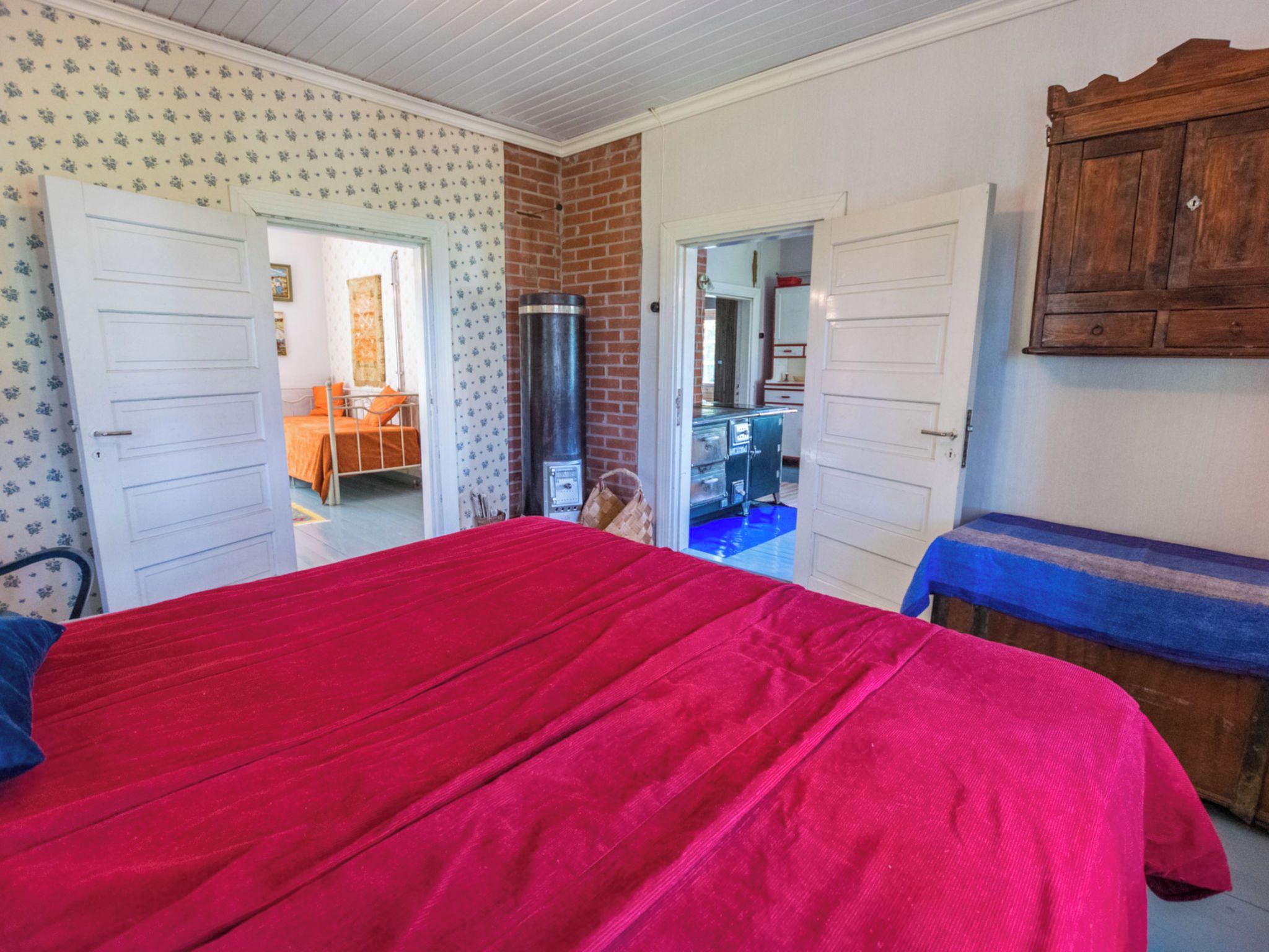 Een kamer met een groot bed, een houten garderobe en een badkamer door een geopende deur.