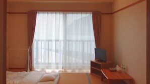 Habitación de hotel con dos camas, televisión, una mesita y una ventana con cortinas.
