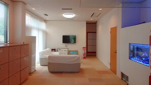 Habitación de hotel moderna con cama, televisión, acuario y minibar.