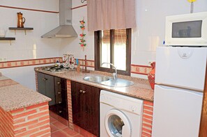 A compact kitchen with a built-in washing machine, a microwave, and a sink.