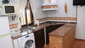A compact kitchen with a washing machine, a microwave, a sink, and a stove.