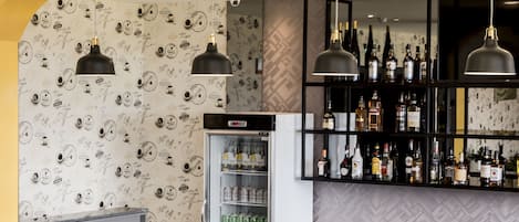 A bar area with a long counter, wicker chairs, and a wall of liquor bottles.