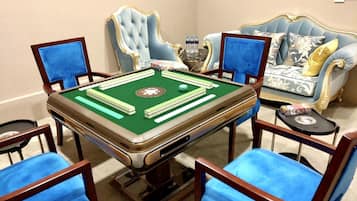 A room with a pool table, four blue chairs, a blue sofa, and a decorative vase.