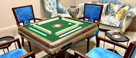 A room with a pool table, four blue chairs, a blue sofa, and a decorative vase.