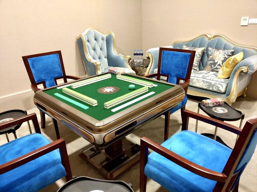 A room with a pool table, four blue chairs, a blue sofa, and a decorative vase.