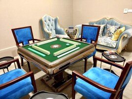 Una habitación con mesa de billar, cuatro sillas azules, un sofá azul y un jarrón decorativo.