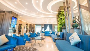 Un vestíbulo moderno con sofás azules, un techo curvo y un jardín vertical verde.