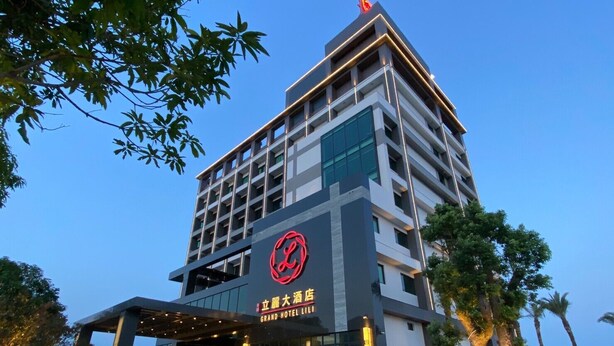 Un hotel de varios pisos con un logotipo rojo llamativo y señalización que dice 'Grand Hotel Li'.