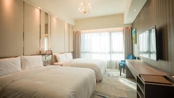 Une chambre d’hôtel avec deux lits, un bureau, une télévision et un lustre.