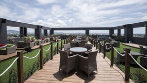 Una terraza en la azotea con mobiliario de mimbre, una cubierta de madera y vistas a la ciudad.