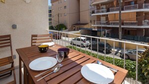 A balcony with a wooden table set for two, a bowl, and a wine glass. - Apartment Alda by Interhome (Segur de Calafell)