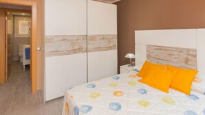 A bedroom with a bed, a nightstand, a lamp, and a wardrobe. - Apartment Alda by Interhome (Segur de Calafell)