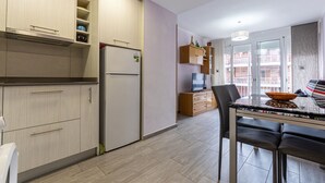 A modern kitchen with a built-in refrigerator, wooden cabinets, and a dining area with a table and chairs. - Apartment Alda by Interhome (Segur de Calafell)