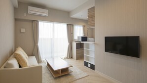 Una sala de estar moderna con un sofá, una mesa de centro, un televisor de pantalla plana y estanterías empotradas.