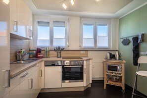 A modern kitchen with built-in appliances, a dishwasher, and a microwave on a small cart.