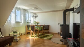 Moderni olohuone, jossa on ruokailutila, takka ja suuri ikkuna.
