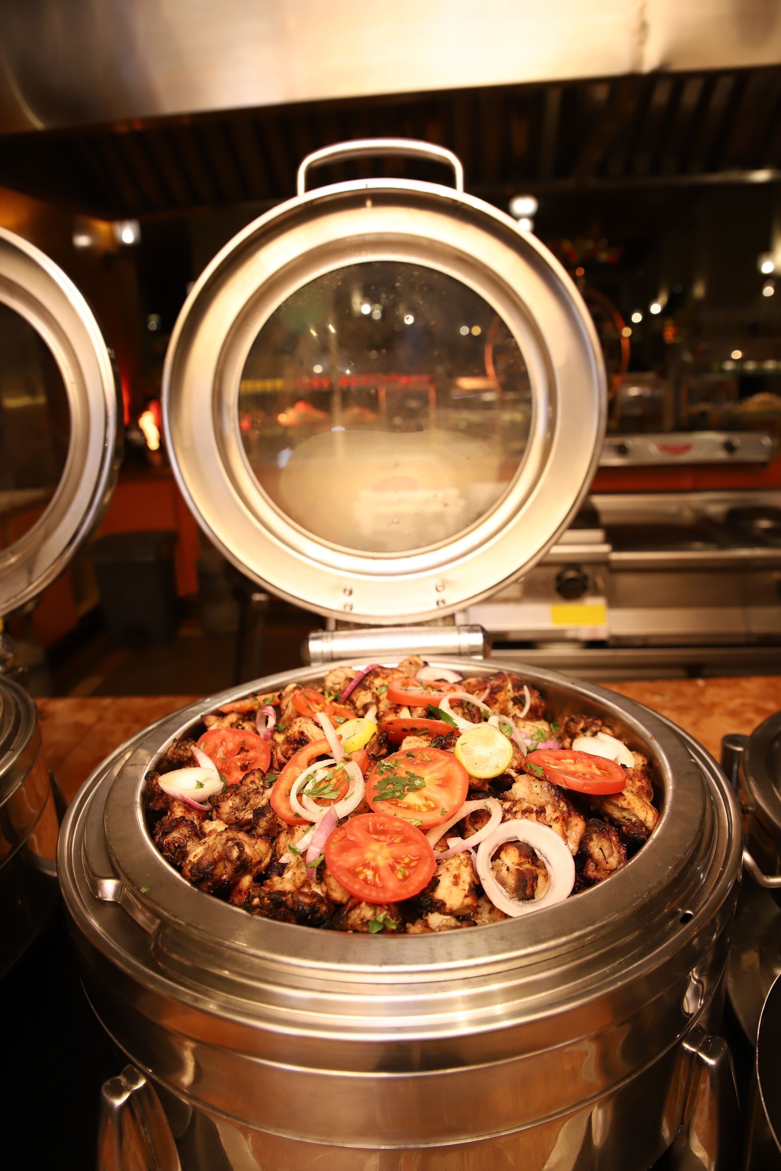 A large, stainless steel pot filled with food, possibly a stew or casserole, with a lid open to reveal the contents.