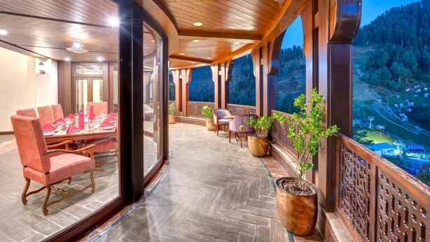 A spacious balcony with a wooden ceiling, a dining area with red chairs, and potted plants. - Pearl Continental Hotel Malam Jabba (Swat)