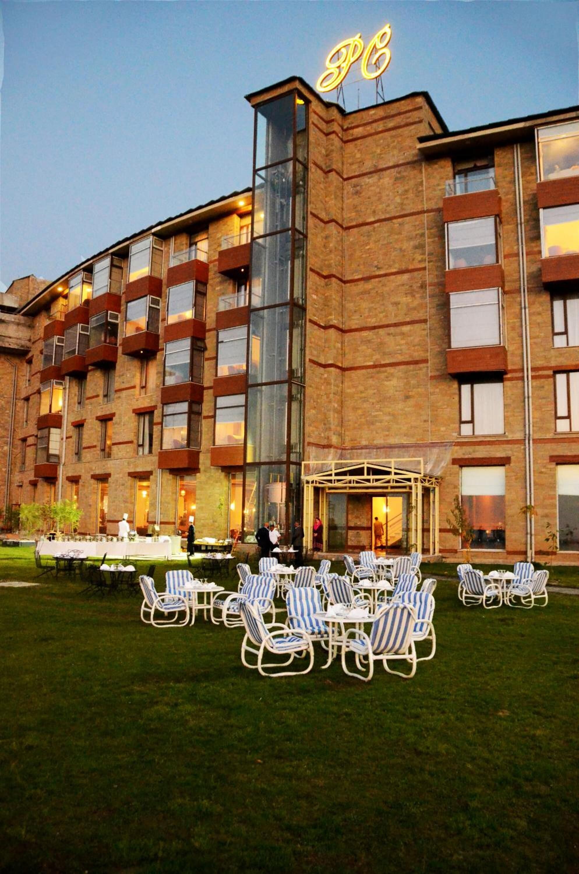 Un hôtel à la façade en briques, doté de nombreux balcons et d’une entrée bien éclairée.