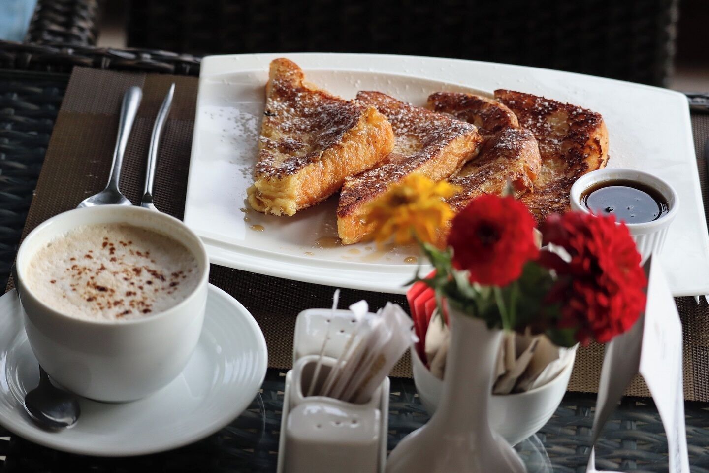 A breakfast setting with toast, coffee, and a small vase of flowers on a table.