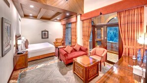 A hotel room with a bed, two sofas, a wooden coffee table, and a desk with a lamp. - Pearl Continental Hotel Malam Jabba (Swat)