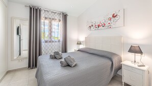 A bedroom with a bed, a nightstand, a lamp, a mirror, and a window with curtains. - Holiday Home “El Rafal de Son Alberti” with Mountain View, Air Conditioning and Pool (Buger)