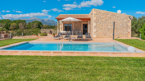 A stone building with a pool, outdoor seating, and a mountain view. - Holiday Home “El Rafal de Son Alberti” with Mountain View, Air Conditioning and Pool (Buger)