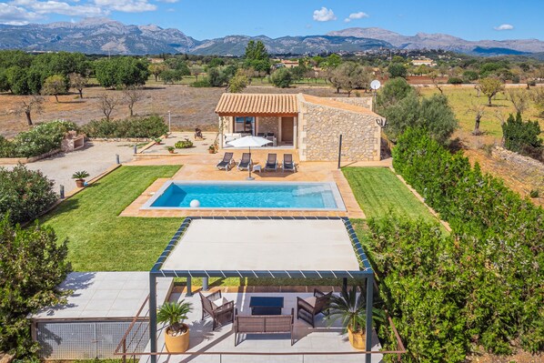 Una villa con piscina, mobiliario exterior y vistas a las montañas.