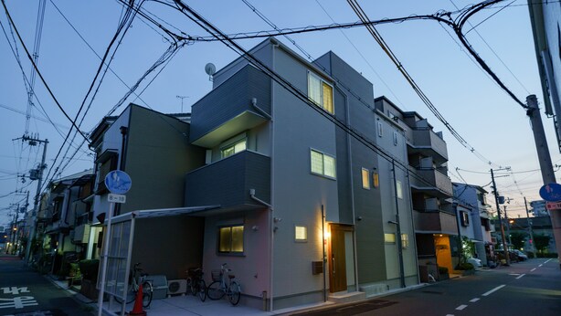 A modern apartment building with a balcony, a bicycle parked outside, and visible power lines. - osaka yeon house (Osaka)