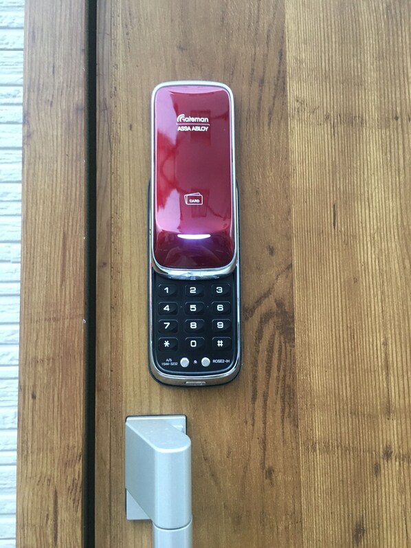 A red mobile phone with a keypad and a card slot on a wooden surface. - osaka yeon house (Osaka)