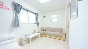 A modern, well-lit room with a sofa, a small table, and a bed. - osaka yeon house (Osaka)