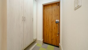 A hallway with a wooden door, a light-colored wardrobe, and a checkered floor. - osaka yeon house (Osaka)