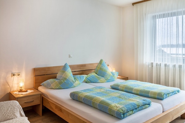 Une chambre à coucher avec un lit en bois, une table de chevet avec une lampe et une fenêtre avec des rideaux.