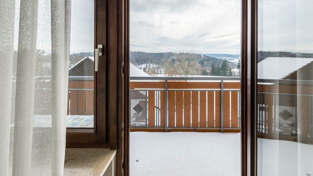 A balcony with a view of a snowy landscape and a wooden fence.