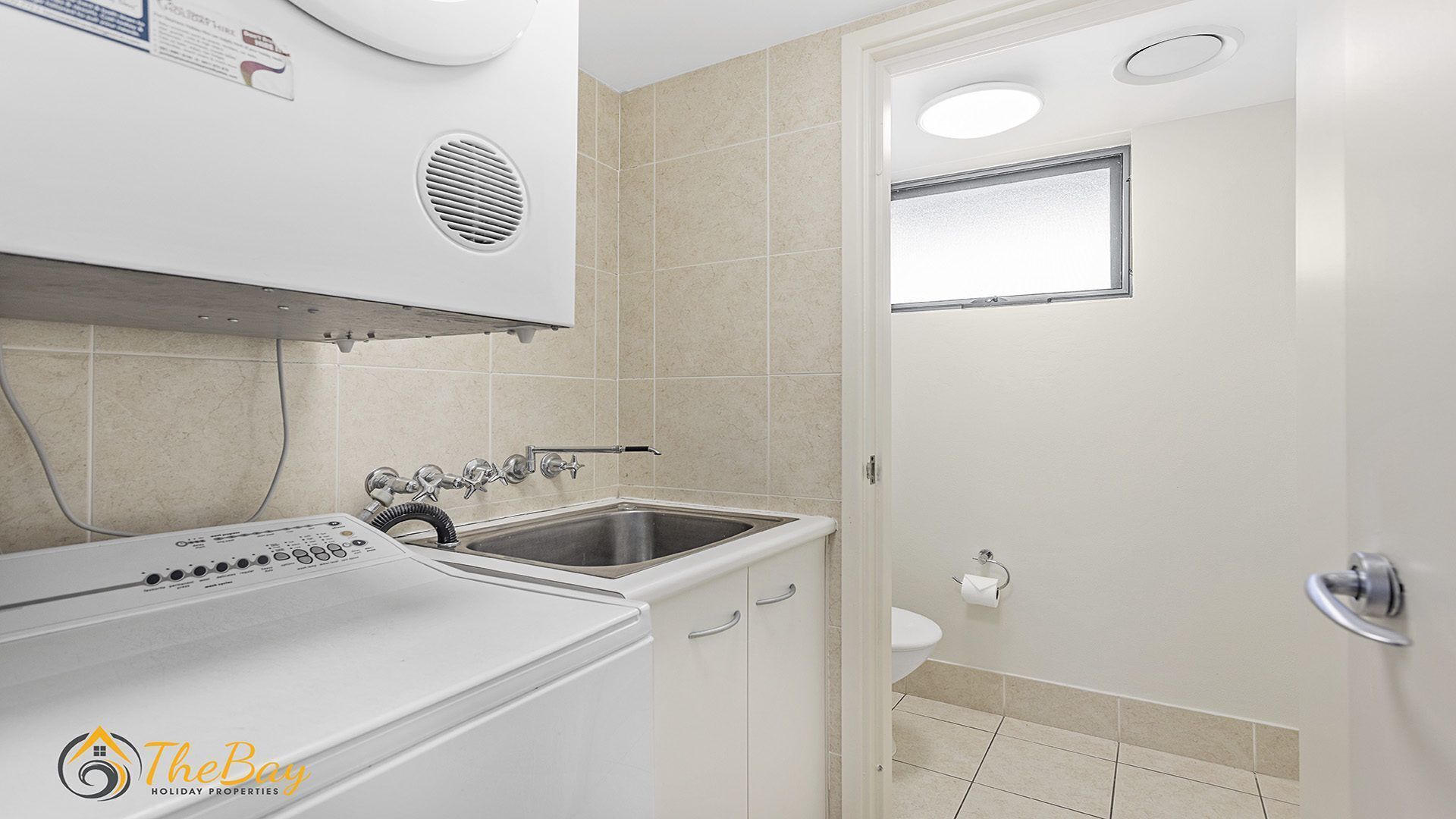 Ein kleines Badezimmer mit Waschmaschine, Waschbecken und Toilette.